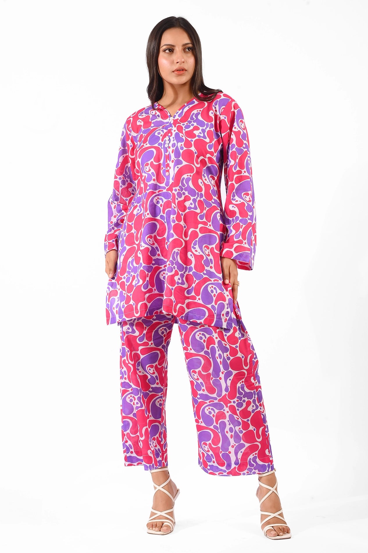 Full-body view of a model wearing a vibrant printed kurta and pants in shades of pink and purple. BOLDSTEP BOLDSTEP.PK