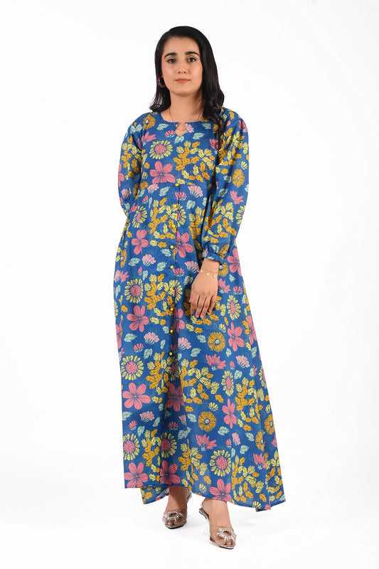 A model wearing a blue maxi dress with vibrant floral prints featuring yellow, pink, and green flowers. The dress has a modest round neckline with a small cutout and long sleeves, paired with silver heels for an elegant look. BOLDSTEP BOLDSTEP.PK