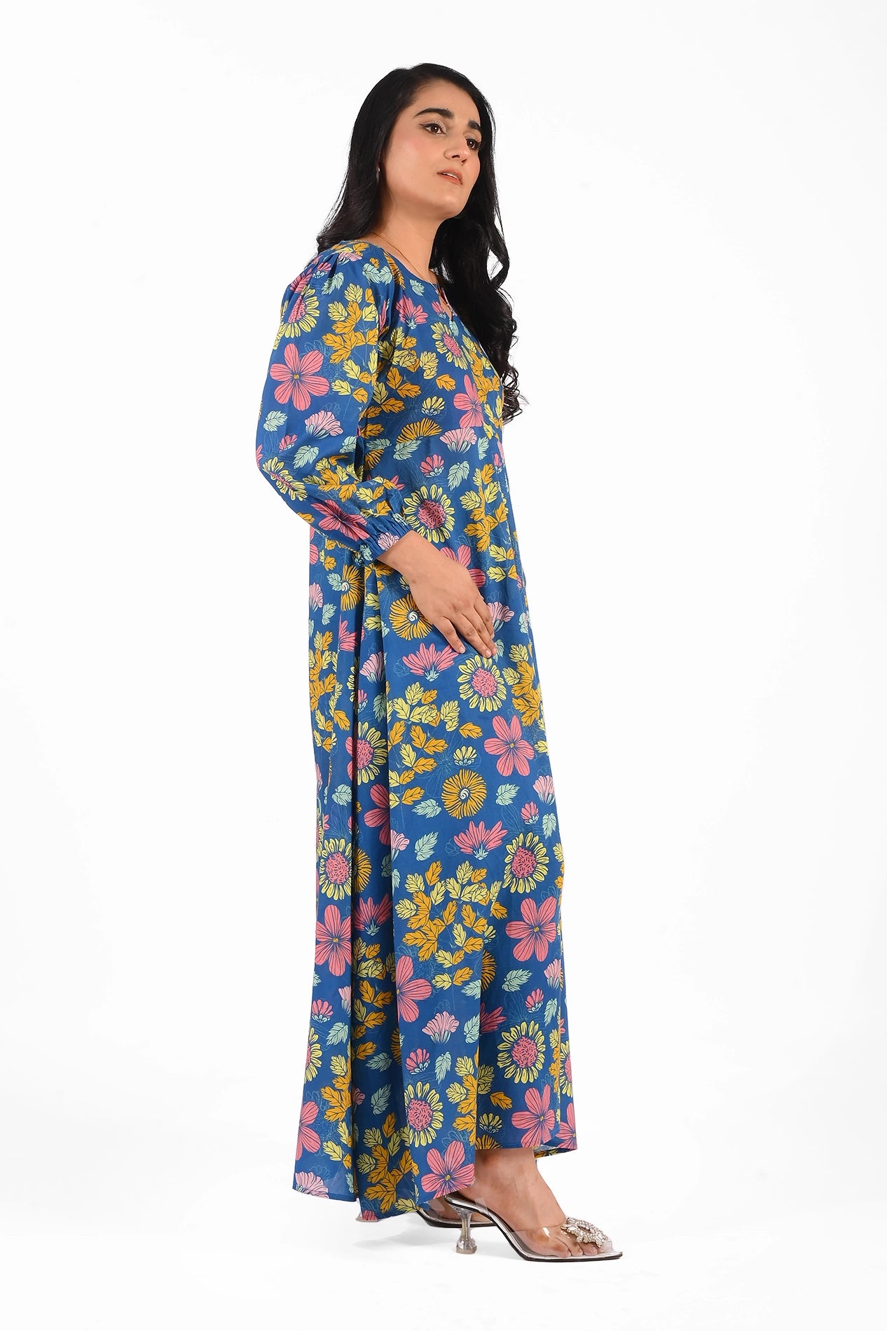 Side view of the blue floral printed maxi dress showcasing its flowing design and long sleeves. The vibrant yellow and pink flower patterns stand out against the blue background. BOLDSTEP BOLDSTEP.PK