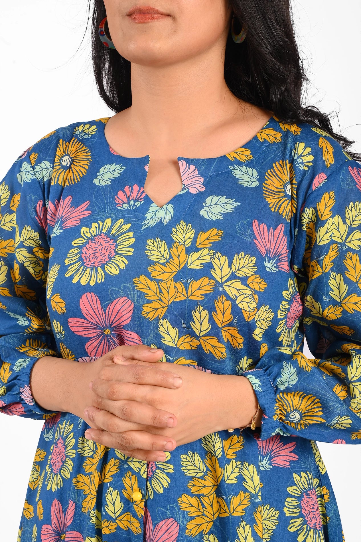 Close-up of the upper part of the dress, emphasizing the neckline with a unique cutout detail and vibrant floral patterns, along with the model's folded hands adding grace to the look. BOLDSTEP BOLDSTEP.PK
