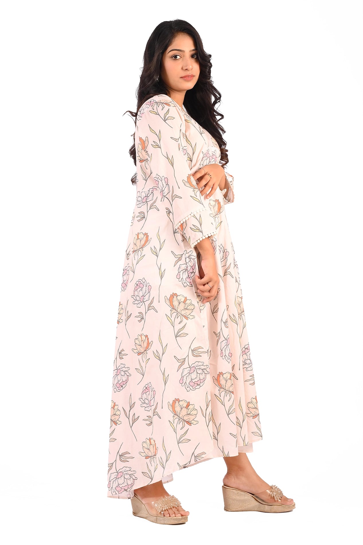 Side profile of a model wearing a pastel pink floral dress. The dress displays a graceful flared design, complemented by its subtle floral patterns and lace detailing on the cuffs. BOLDSTEP BOLDSTEP.PK
