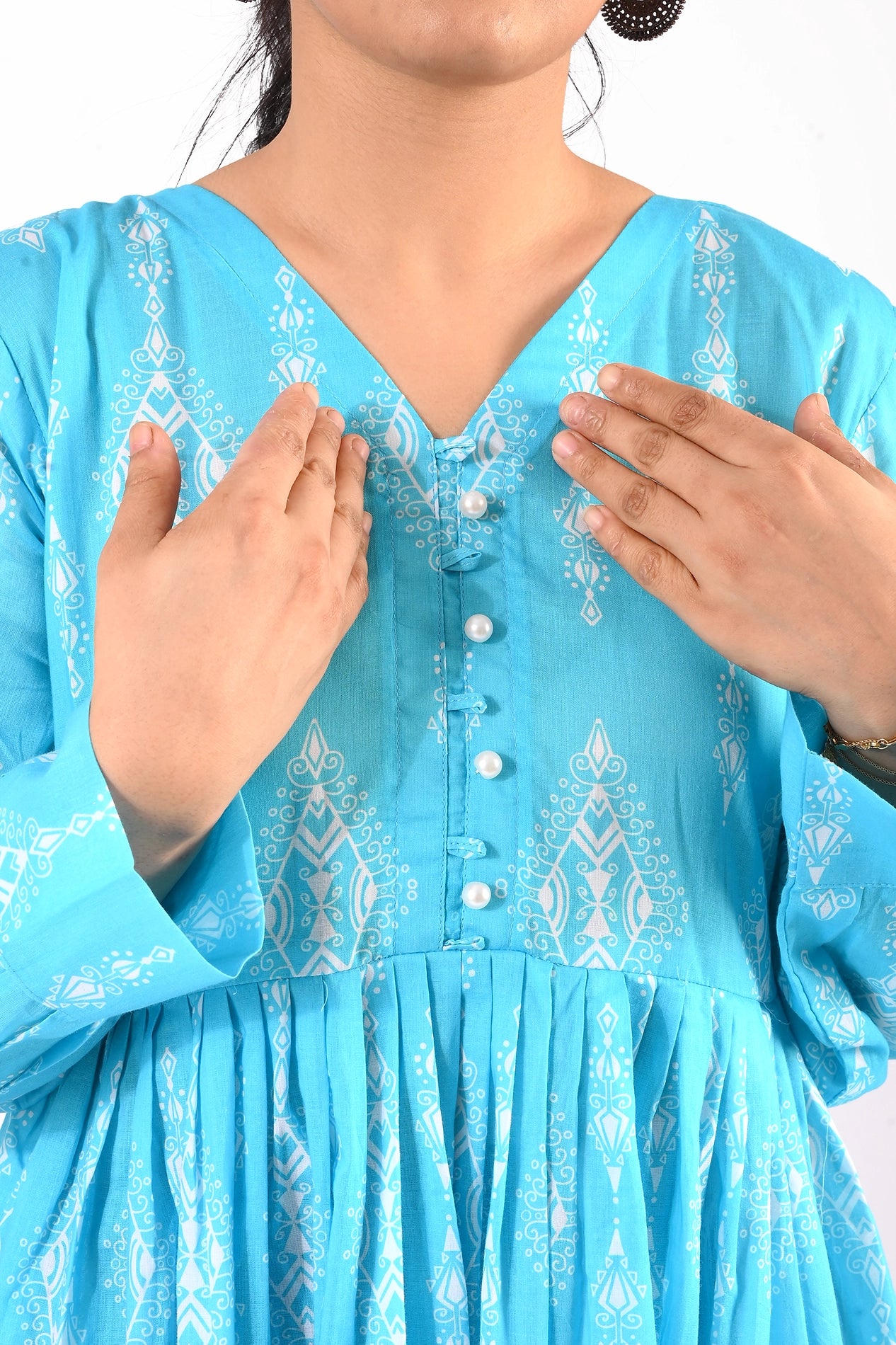 A close-up of the bodice of the dress highlighting the V-neckline, button detailing, and pleated waist design. boldstep boldstep.pk