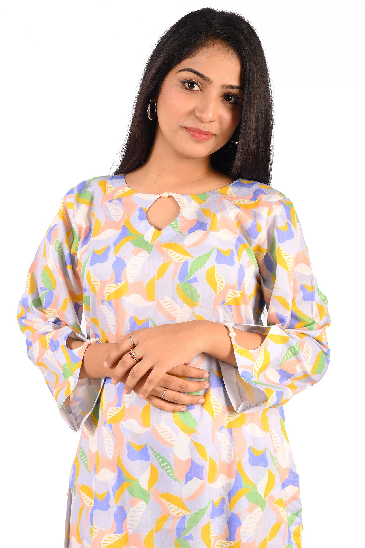 A close-up of a young woman wearing a pastel-colored floral leaf patterned dress. The dress features a teardrop neckline with a pearl clasp, adding a delicate detail to the outfit. Her soft expression complements the feminine charm of the attire BOLDSTEP BOLDSTEP.PK