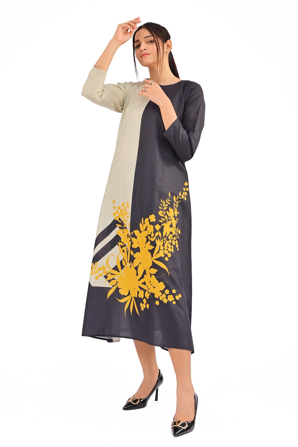 A model wearing a long, color-blocked dress featuring beige and black panels with yellow floral detailing, paired with black high heels, striking a chic pose BOLDSTEP BOLDSTEP.pk
