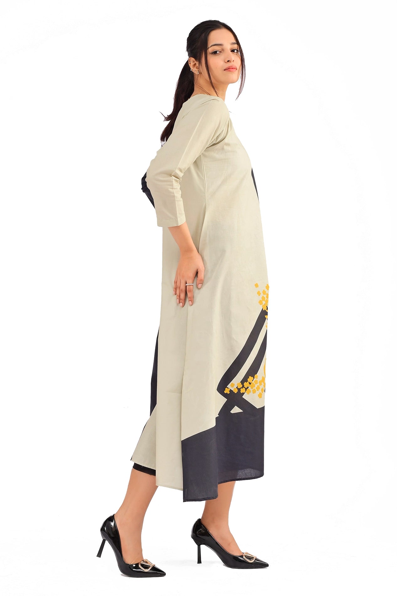 Side profile of a model showcasing the long, dual-toned dress with beige on one side and black on the other, emphasizing its floral yellow accents. BOLDSTEP BOLDSTEP.PK