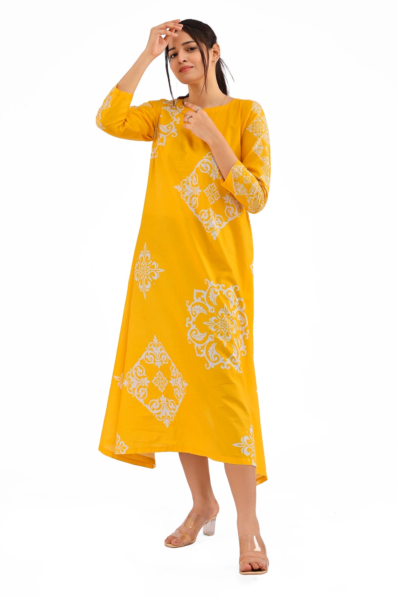 A vibrant yellow long dress adorned with elegant white floral and geometric block patterns. The model poses gracefully, showing the full front view of the dress, with three-quarter sleeves and a rounded neckline. BOLDSTEP BOLDSTEP.PK