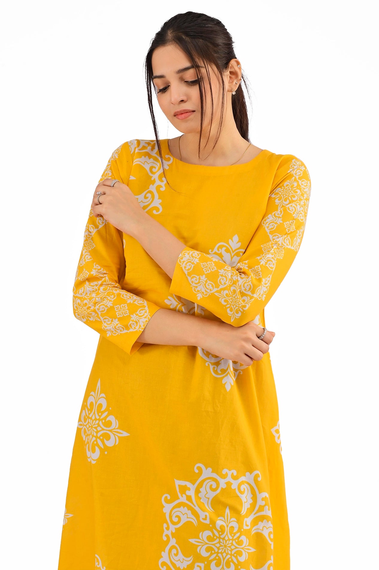 Close-up front view of the yellow dress focusing on its rounded neckline and intricate white block patterns on the bodice and sleeves. The model strikes a thoughtful pose. BOLDSTEP BOLDSTEP.PK