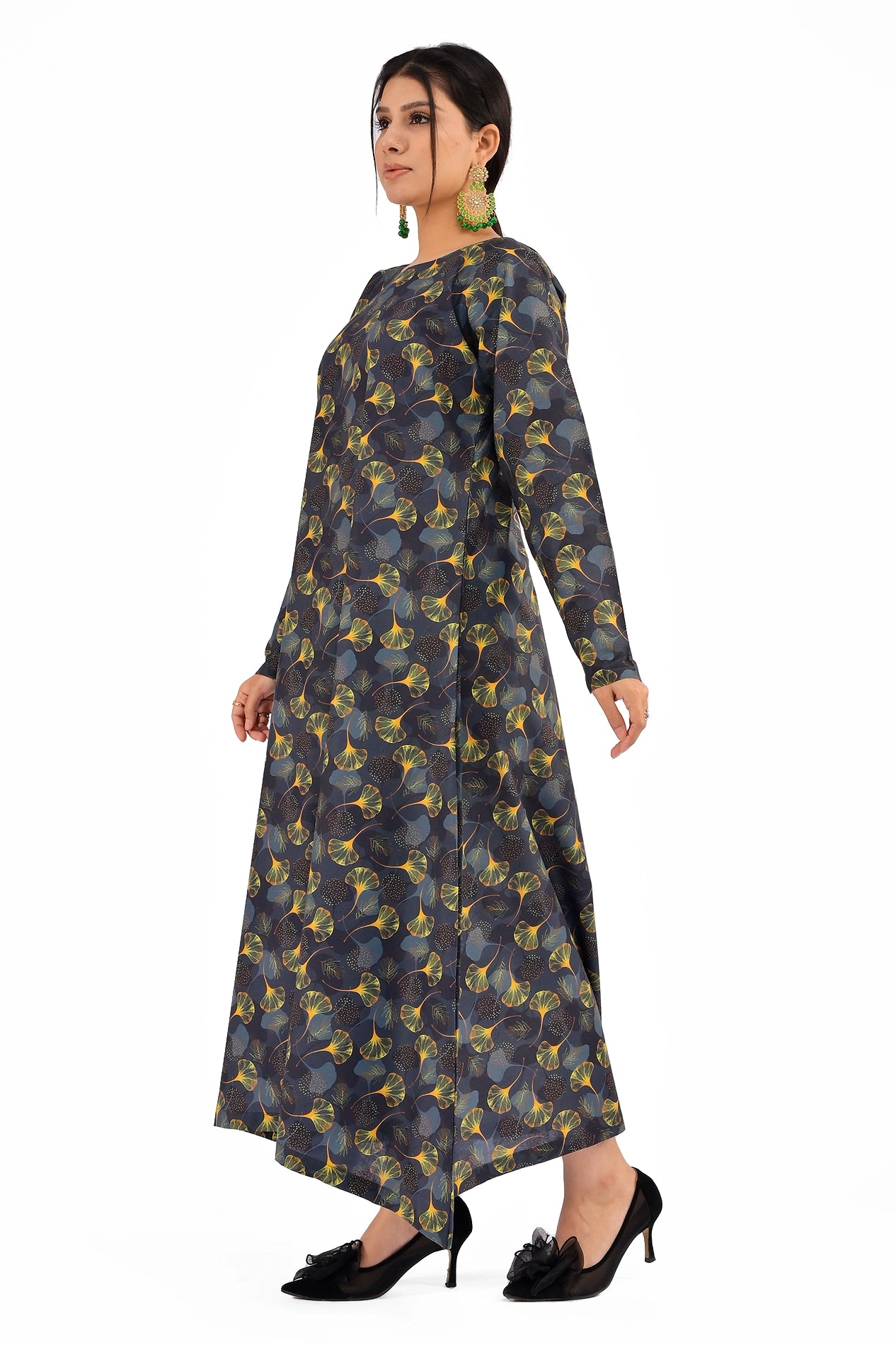 A side profile of the model showcasing the black ginkgo leaf patterned dress, emphasizing the structured full sleeves and the graceful flare of the A-line design. BOLDSTEP BOLDSTEP.PK