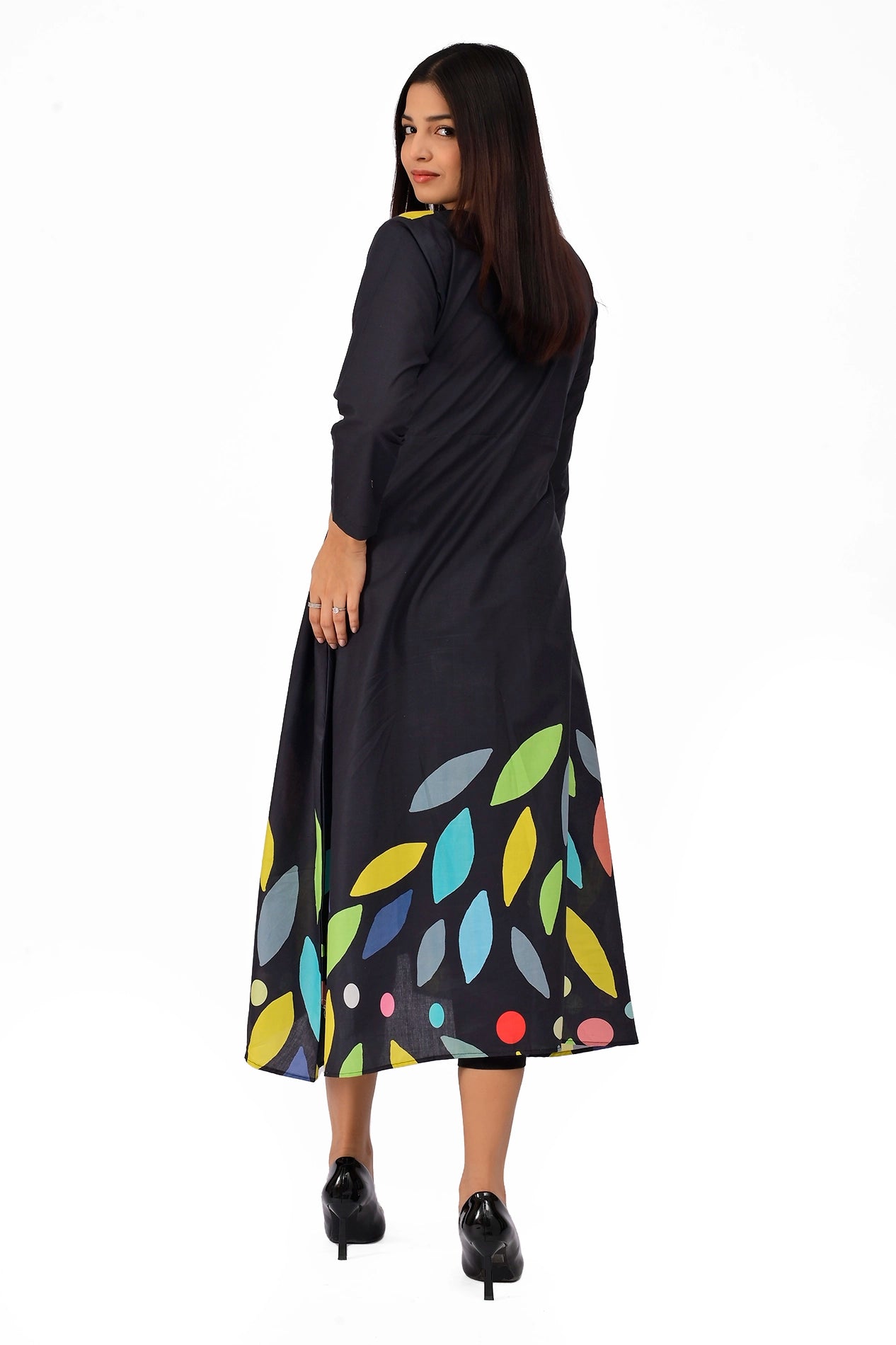 Rear view of a black A-line dress featuring vibrant leaf patterns in shades of green, blue, yellow, and orange, modeled with elegance. BOLDSTEP BOLDSTEP.PK