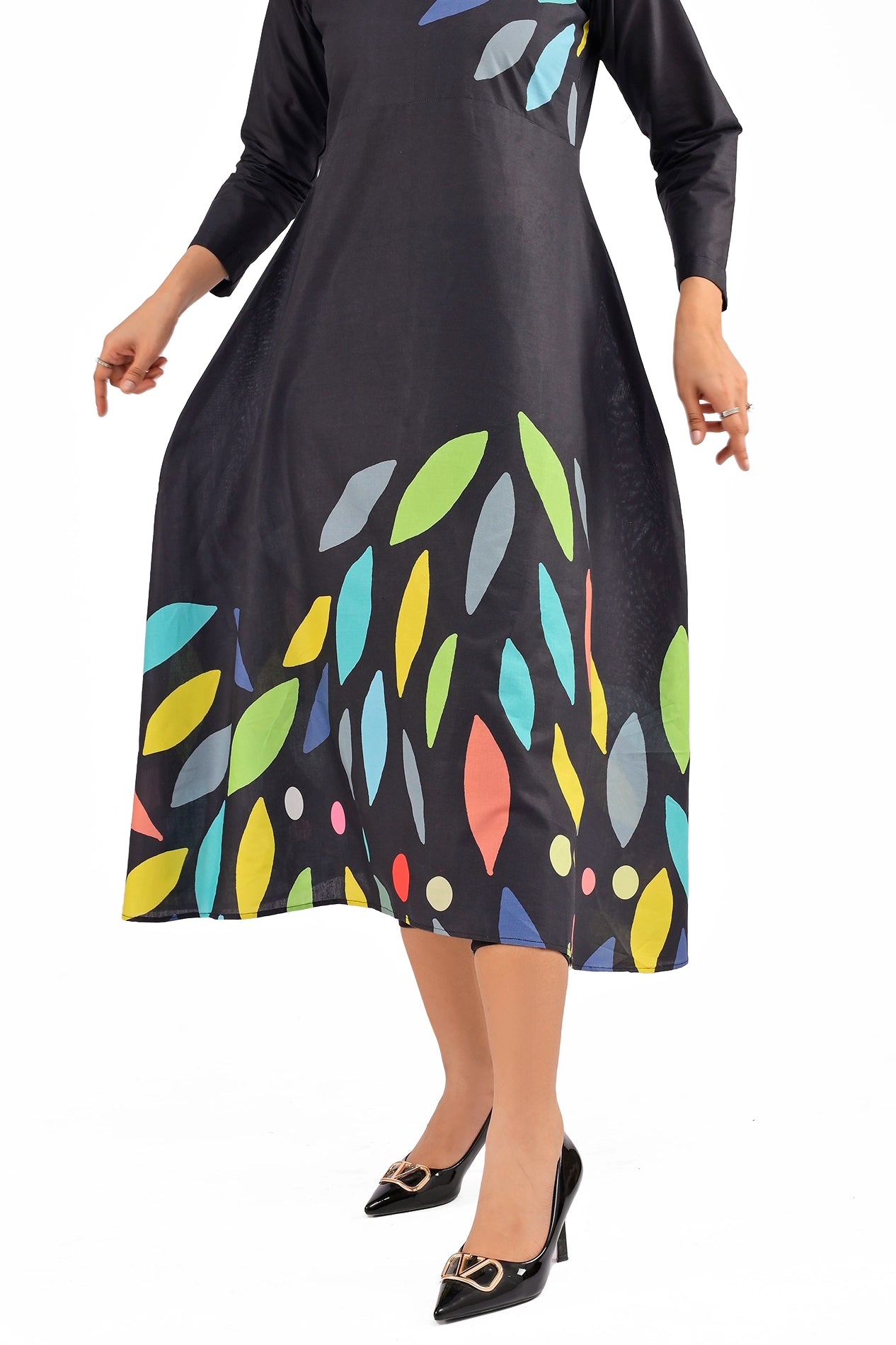 Full-length view of a flowy black dress adorned with bold multicolored leaf motifs, paired with stylish black heels, highlighting the modern A-line silhouette. BOLDSTEP BOLDSTEP.PK