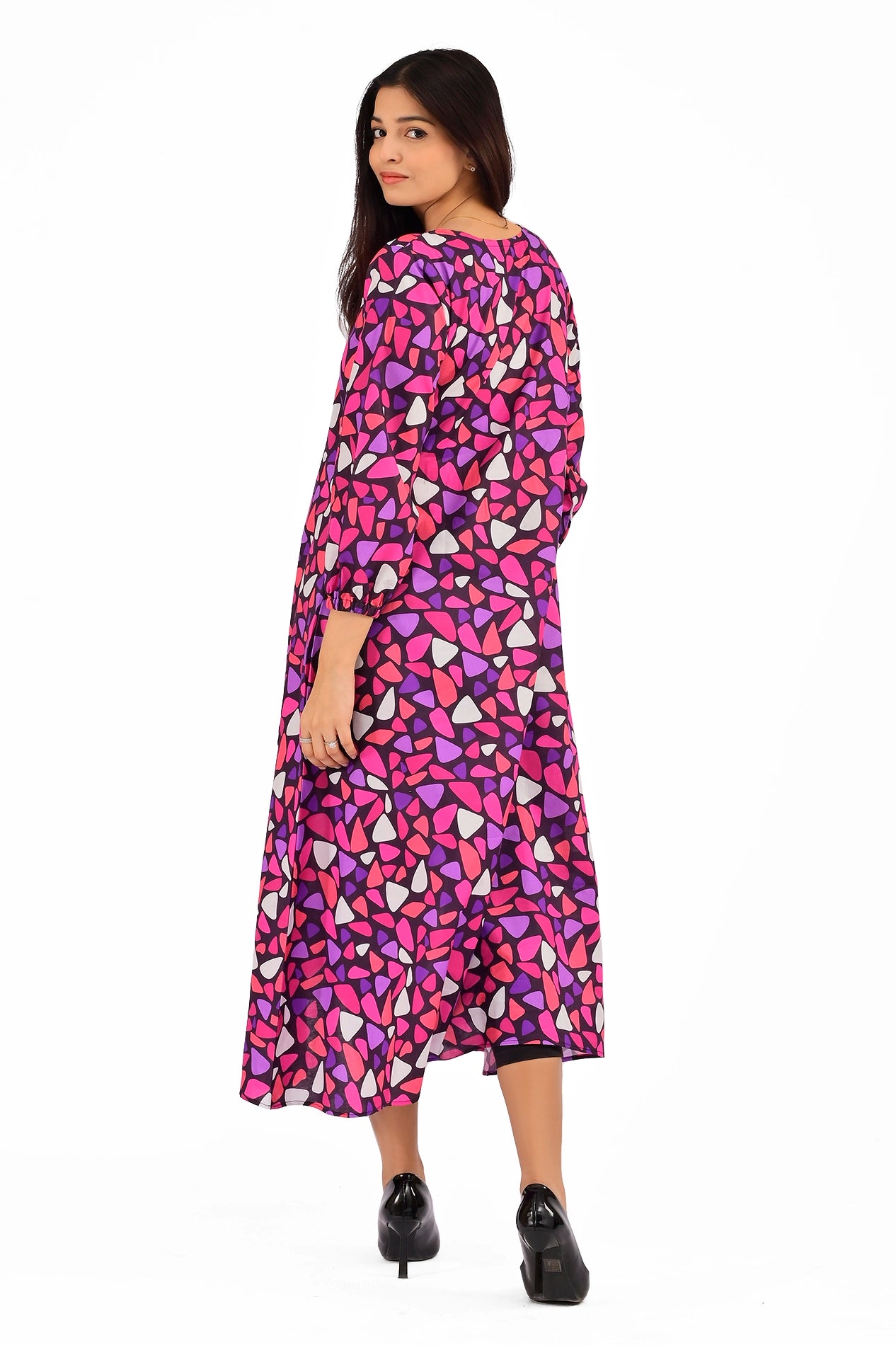Back view of a woman modeling a pink, purple, and white mosaic-printed dress, highlighting the modest midi length and stylish puffed sleeves. BOLDSTEP BOLDSTEP.PK