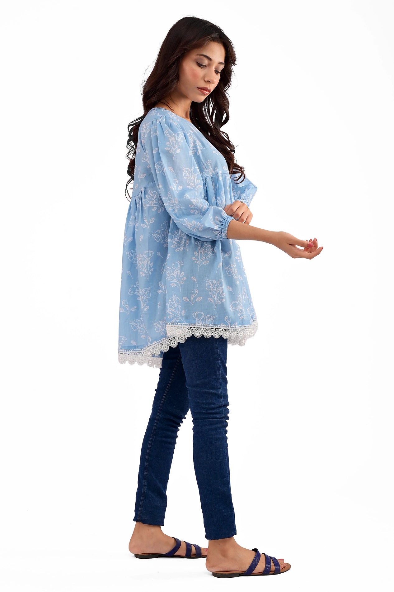 A side profile of the model showcasing the flowy silhouette of the tunic, highlighting the delicate floral print and soft gathers that add movement