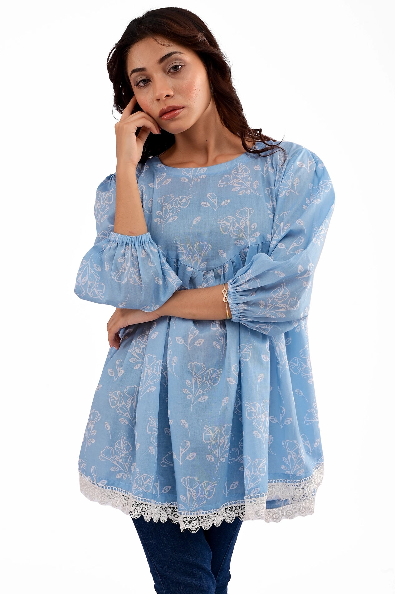 A detailed close-up of the tunic's floral pattern, soft pleats, and elasticized sleeves, showcasing the fine stitching and delicate lace trim