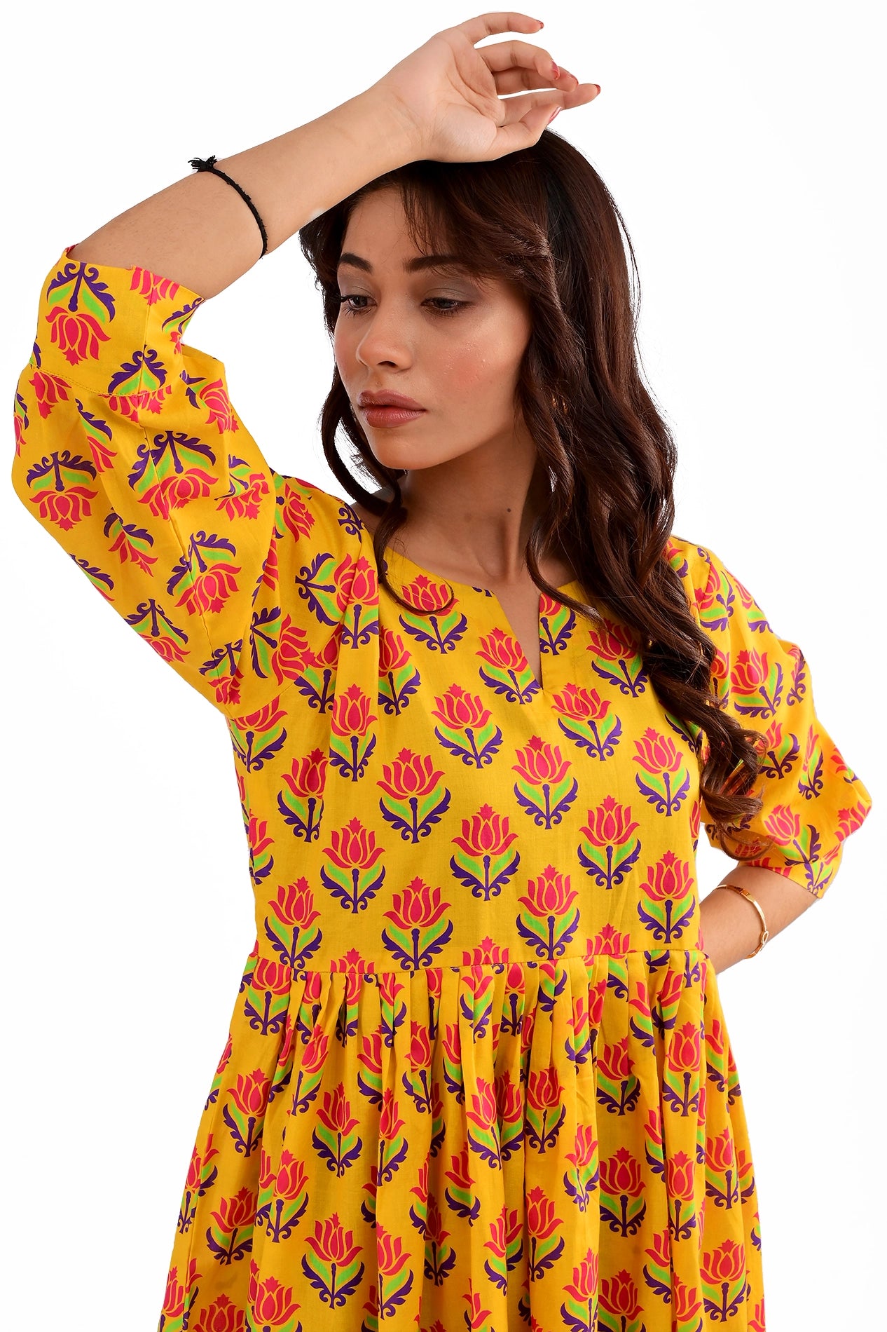 close-up of the model highlighting the notched neckline and the intricate floral print on the yellow tunic, accessorized with silver jewelry