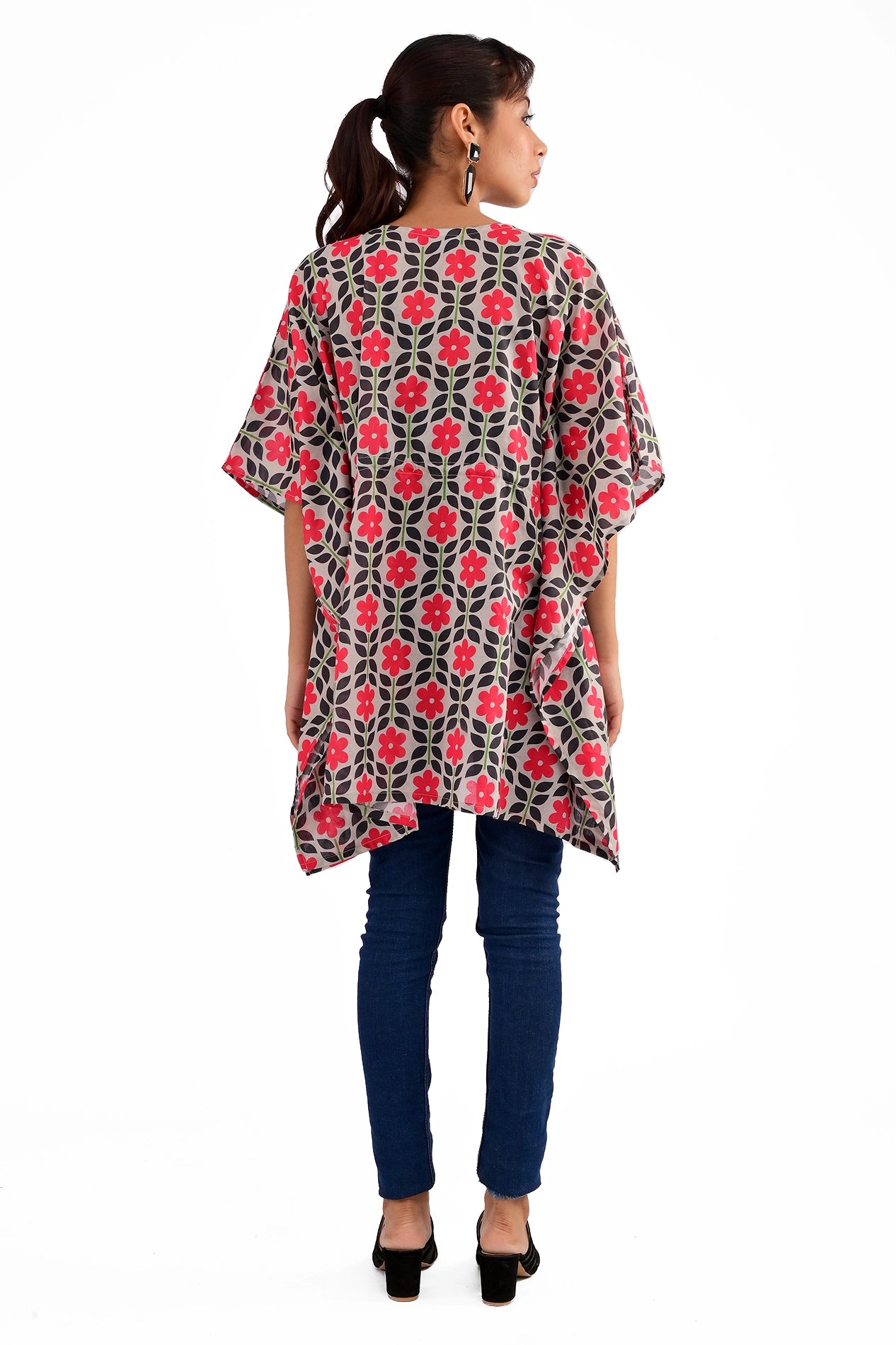 A full-length shot from the back, showcasing the loose-fitting kaftan-style tunic with a red floral pattern against a black background
