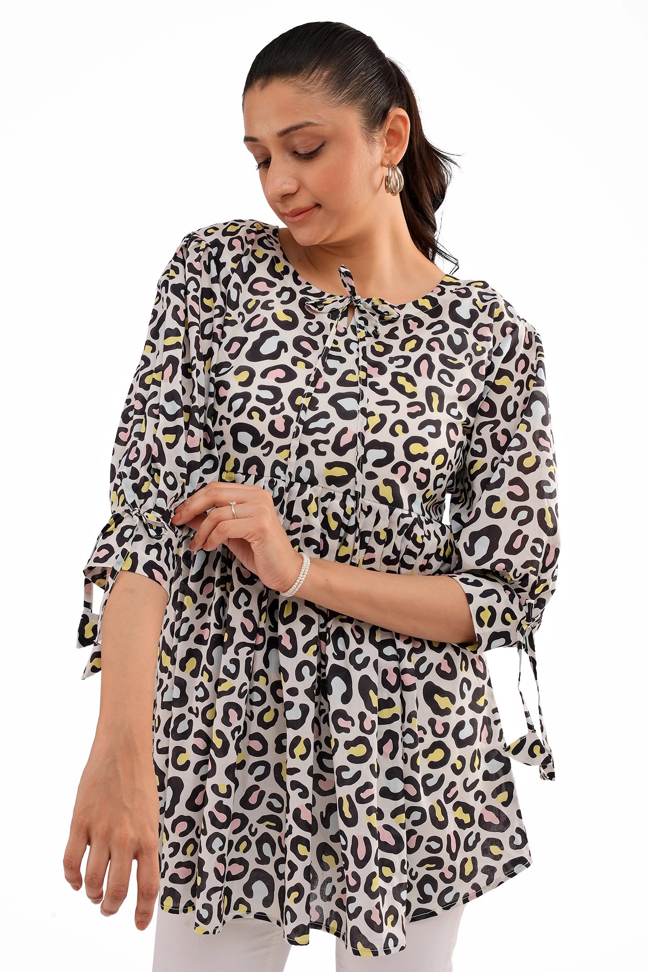 A close-up shot highlighting the tie-neck detail of the leopard print tunic. The fabric features a soft drape, with subtle pastel tones adding elegance to the bold print
