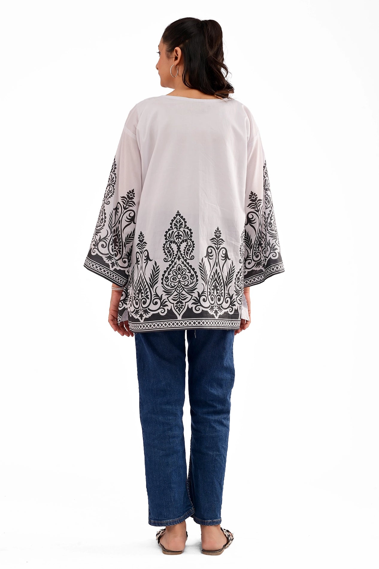 The backside of a white lawn kurti featuring black symmetrical motifs along the lower hem and sleeves, worn with blue jeans