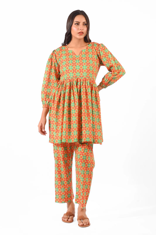 A model wearing a vibrant orange and green patterned dress with puffed sleeves, styled with matching straight pants and flat sandals. The outfit features a gathered waistline and a V-neckline, captured from the front BOLDSTEP  BOLDSTEP.PK