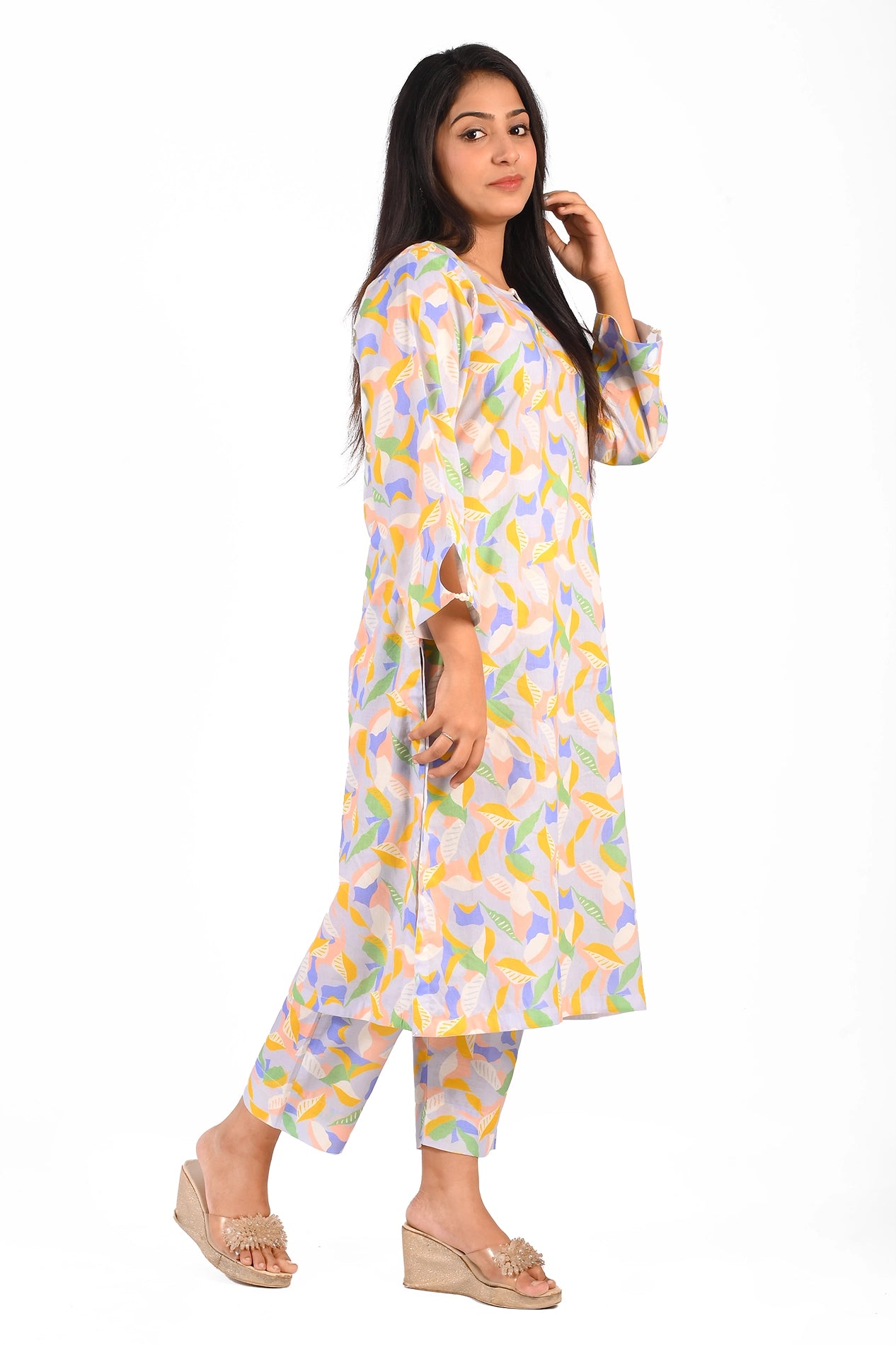 A side view of a young woman showcasing her pastel-colored floral leaf patterned dress. The dress is complemented with straight-fit trousers, perfect for a breezy and casual look. Her relaxed posture highlights the flowy and comfortable fit of the outfit BOLDSTEP BOLDSTEP.PK