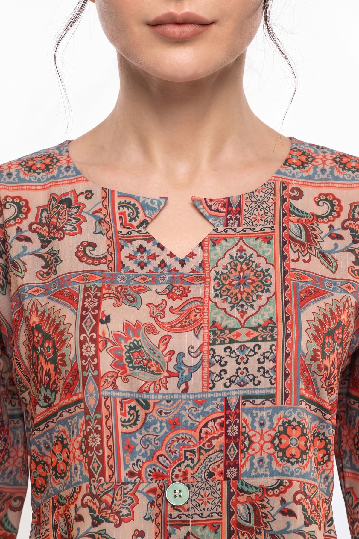 Close-up view of V-notch slit neckline featuring mint button on beige mosaic tile print fabric.