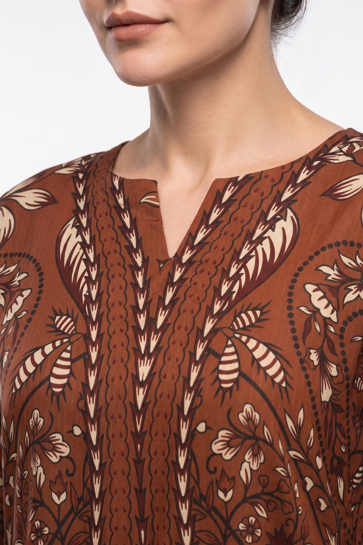 Close-up view of V-notch neckline on rust brown batik printed Swiss Bana Dora fabric.