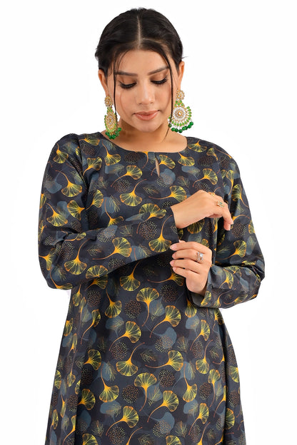 A close-up of the model adjusting the sleeve cuff of the black dress with vibrant yellow and green ginkgo leaf patterns, showcasing the fabric texture and design details. BOLDSTEP BOLDSTEP.PK