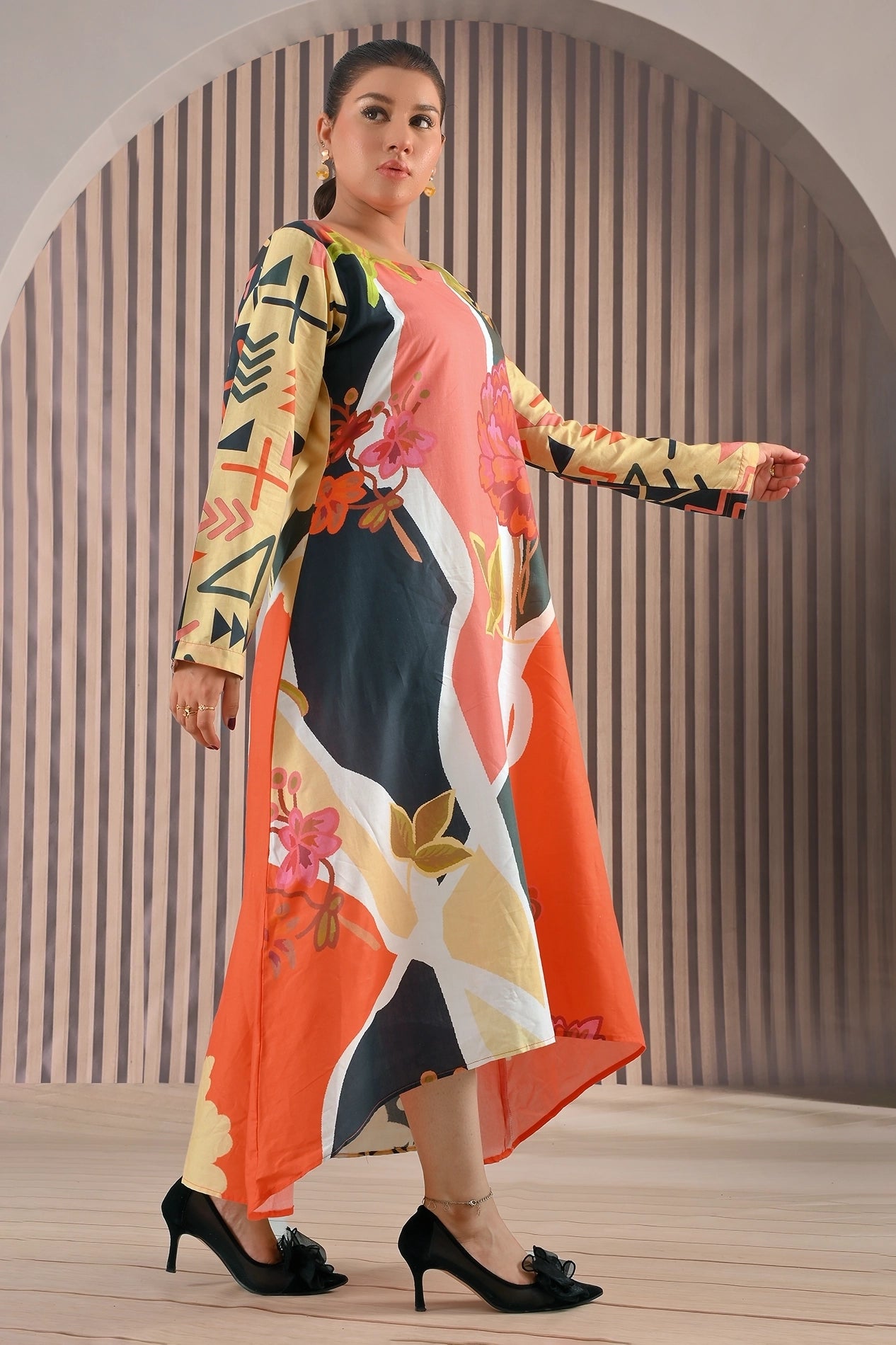 Side angle view of BOLDSTEP floral abstract maxi dress highlighting vibrant coral orange and mustard hues with full-length printed sleeves and flowy hemline | BOLD STEP | BOLDSTEP.PK | BOLDSTEP STORE.